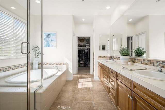 full bath with a walk in closet, a garden tub, a sink, and double vanity