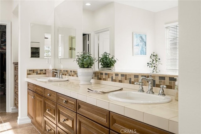 full bathroom featuring a walk in closet, a sink, backsplash, and double vanity