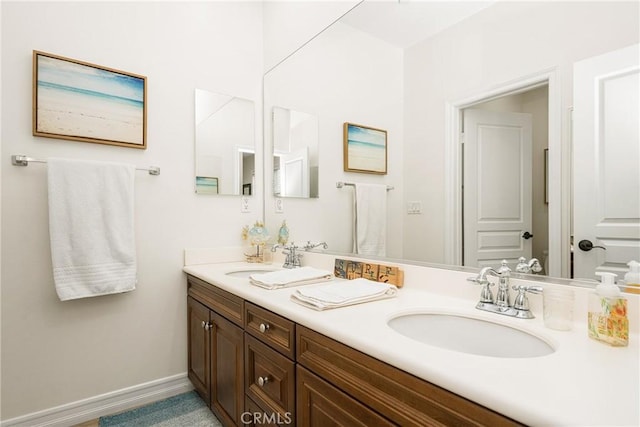 bathroom featuring double vanity, baseboards, and a sink