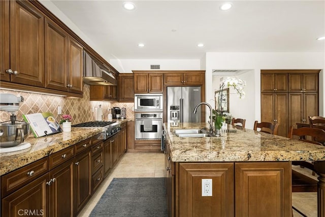 kitchen featuring stainless steel appliances, a breakfast bar, and an island with sink