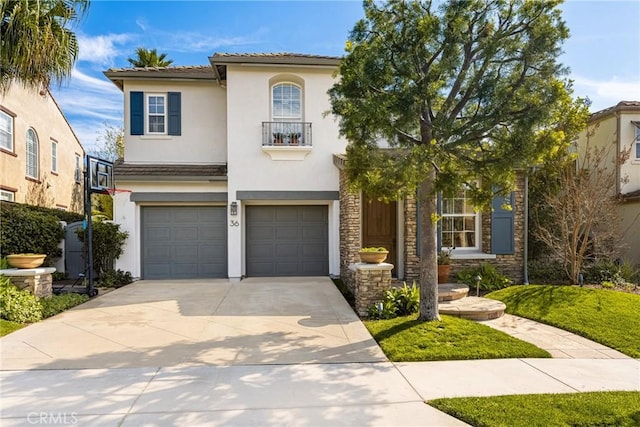 mediterranean / spanish-style house with driveway, a balcony, stone siding, an attached garage, and stucco siding