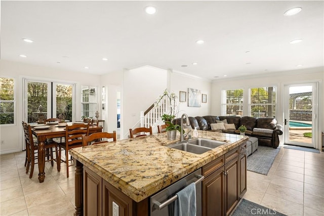 kitchen featuring a sink, a healthy amount of sunlight, open floor plan, stainless steel dishwasher, and an island with sink