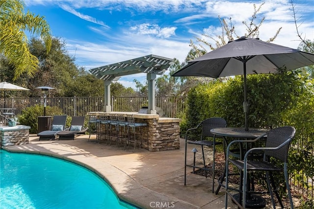 view of swimming pool featuring a patio area, fence, and outdoor dry bar