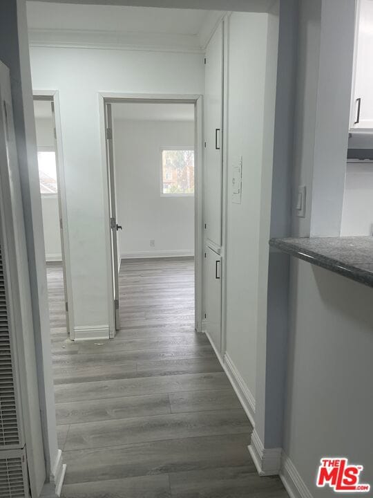 hallway with ornamental molding and light hardwood / wood-style floors