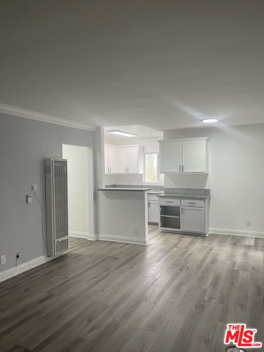 unfurnished living room with hardwood / wood-style flooring and crown molding