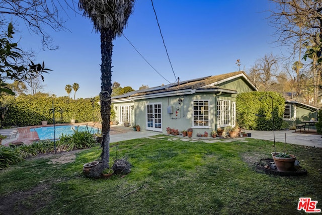 rear view of property with a patio, an outbuilding, a lawn, and french doors