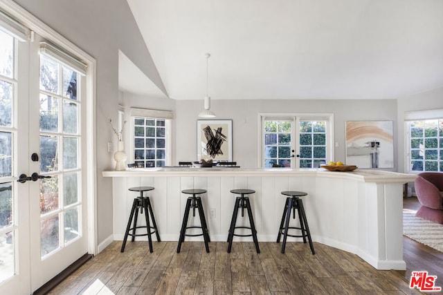 kitchen with vaulted ceiling, dark hardwood / wood-style floors, decorative light fixtures, kitchen peninsula, and french doors