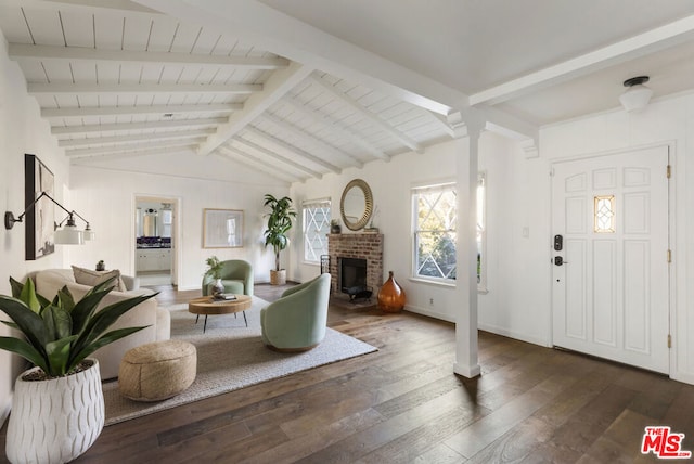 entrance foyer featuring dark wood-type flooring, a fireplace, lofted ceiling with beams, and decorative columns