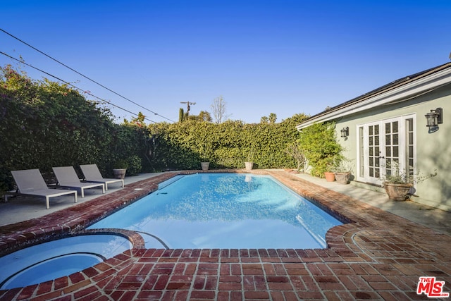 view of pool with a patio, an in ground hot tub, and french doors