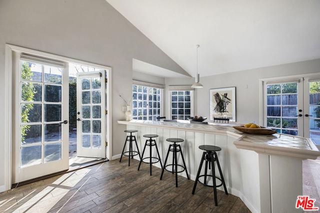 kitchen featuring dark hardwood / wood-style floors, decorative light fixtures, a breakfast bar area, kitchen peninsula, and french doors