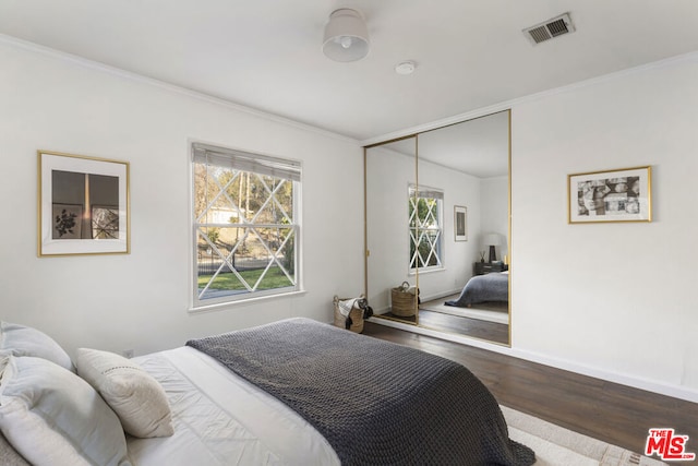 bedroom with ornamental molding, dark hardwood / wood-style floors, and a closet