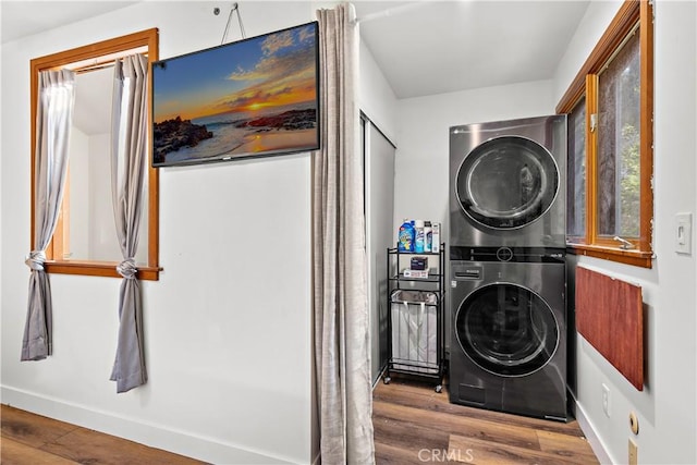 laundry area featuring wood-type flooring and stacked washer / dryer