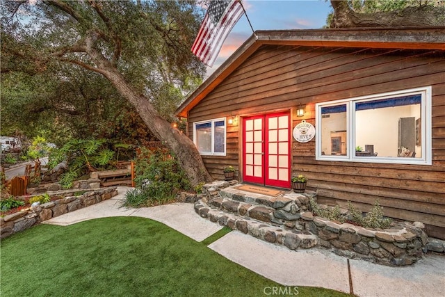 exterior entry at dusk with a yard and french doors