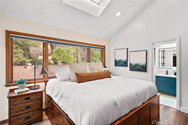 bedroom with ensuite bath, lofted ceiling with skylight, and hardwood / wood-style floors