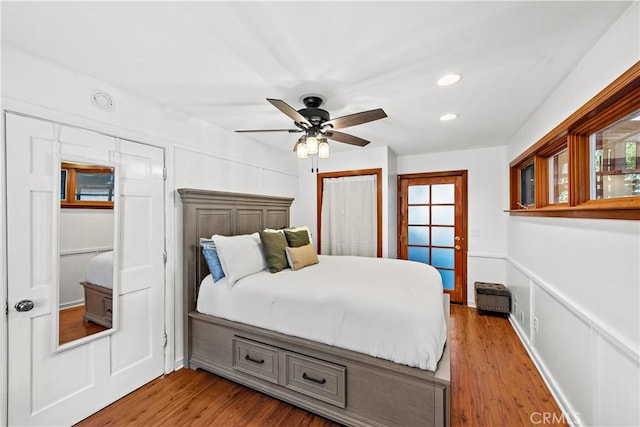 bedroom featuring ceiling fan, hardwood / wood-style floors, and multiple windows