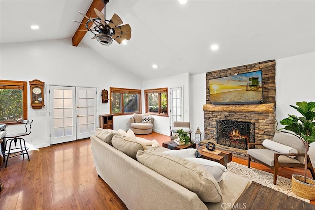 living room featuring hardwood / wood-style floors, high vaulted ceiling, a fireplace, ceiling fan, and beam ceiling