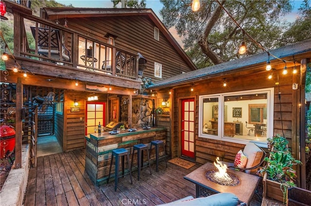 deck at dusk featuring exterior bar and a fire pit