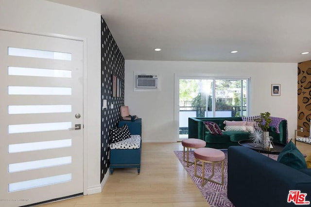 living room featuring a wall mounted air conditioner and light wood-type flooring