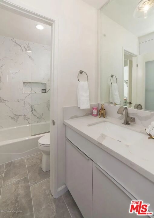 full bathroom featuring vanity, tiled shower / bath combo, and toilet