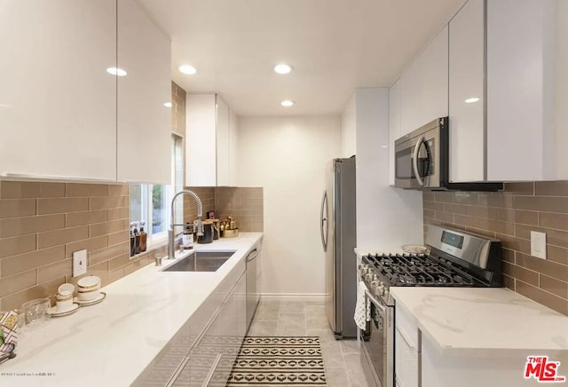 kitchen featuring light stone counters, stainless steel appliances, sink, and white cabinets