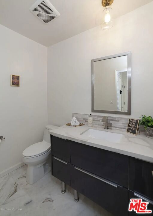 bathroom with vanity, toilet, and backsplash