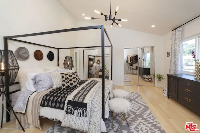 bedroom with lofted ceiling, a notable chandelier, and light hardwood / wood-style flooring