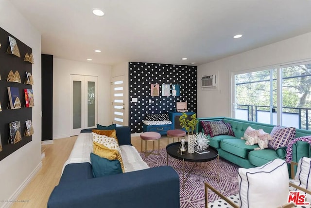 living room featuring light hardwood / wood-style flooring, an AC wall unit, and french doors