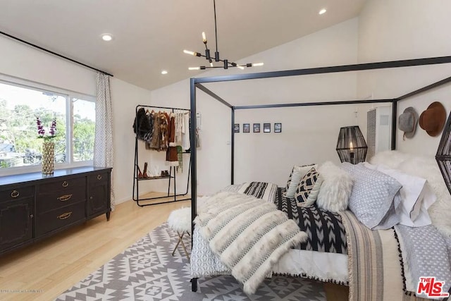 bedroom featuring lofted ceiling, a notable chandelier, and light hardwood / wood-style floors