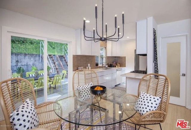 dining space featuring an inviting chandelier, light hardwood / wood-style floors, and sink