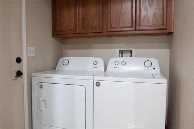 clothes washing area featuring cabinets and separate washer and dryer