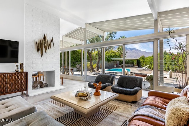 living room with a mountain view, a brick fireplace, and vaulted ceiling with beams