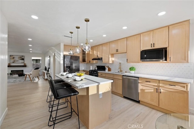 kitchen with a breakfast bar, stainless steel appliances, light brown cabinetry, and a kitchen island