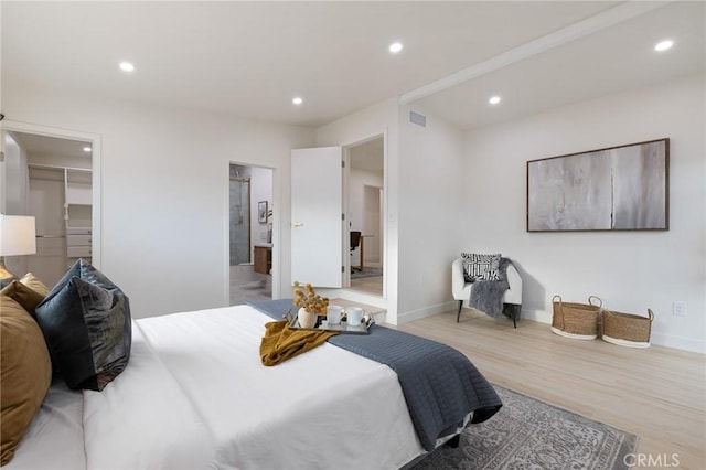 bedroom featuring a walk in closet, ensuite bathroom, and light wood-type flooring