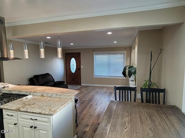 kitchen with range, white cabinetry, ornamental molding, light stone countertops, and light wood-type flooring