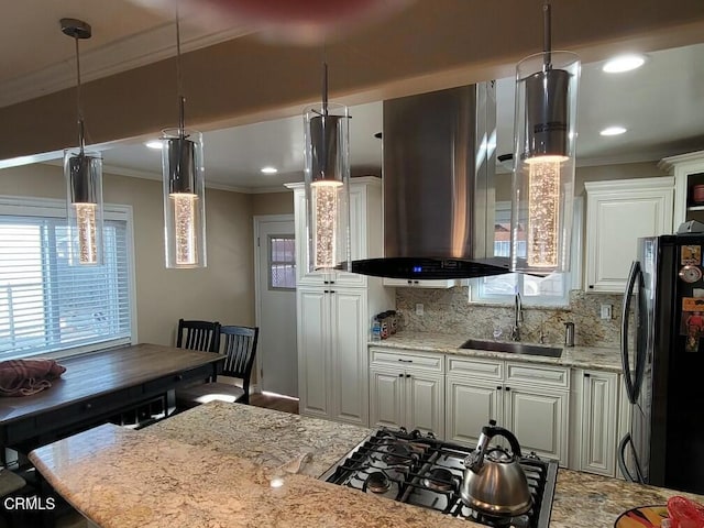 kitchen featuring sink, crown molding, light stone countertops, island exhaust hood, and black fridge