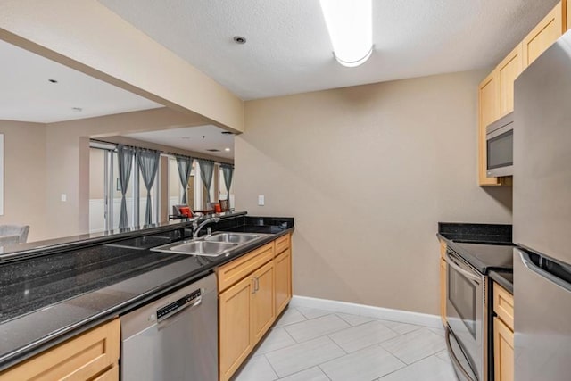 kitchen featuring light tile patterned flooring, sink, light brown cabinets, kitchen peninsula, and stainless steel appliances