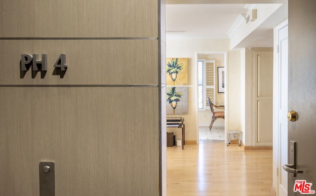 hallway featuring ornamental molding and light hardwood / wood-style floors