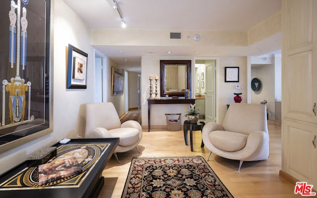 living area with track lighting and light hardwood / wood-style flooring