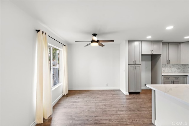 kitchen featuring hardwood / wood-style floors, backsplash, gray cabinets, and ceiling fan