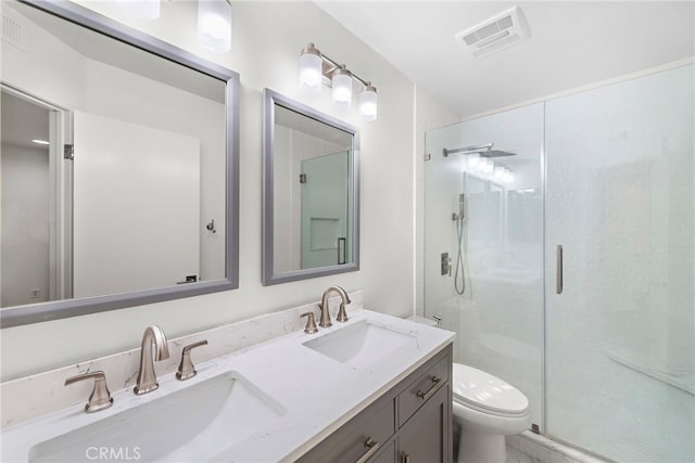 bathroom with a shower with door, vanity, and toilet