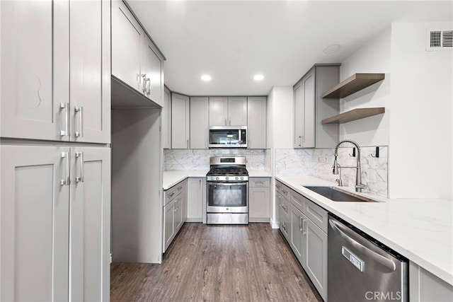 kitchen featuring sink, appliances with stainless steel finishes, dark hardwood / wood-style flooring, gray cabinets, and light stone countertops