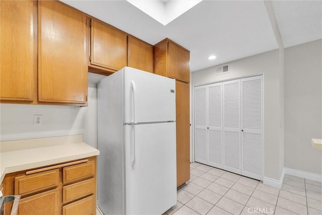 kitchen with light tile patterned floors and white fridge