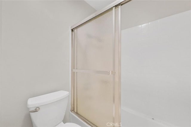 bathroom featuring shower / bath combination with glass door and toilet