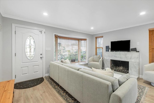 living room featuring crown molding, a fireplace, and light hardwood / wood-style floors