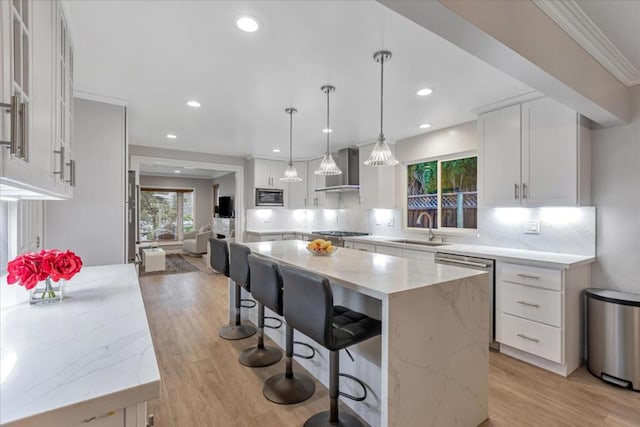 kitchen featuring a kitchen island, decorative light fixtures, dishwasher, sink, and wall chimney exhaust hood