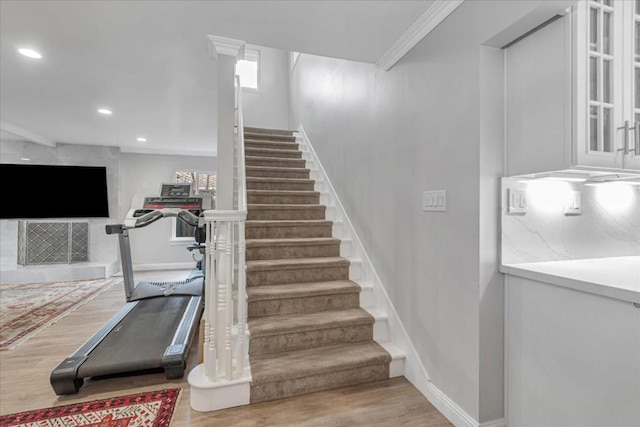 stairs featuring hardwood / wood-style floors and crown molding