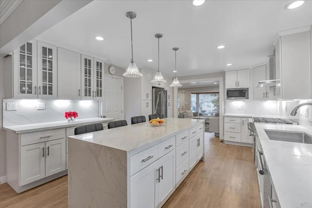 kitchen featuring hanging light fixtures, a center island, white cabinets, built in microwave, and high end refrigerator