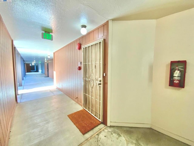 corridor with wooden walls and a textured ceiling