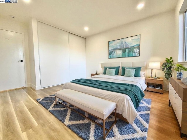 bedroom with light hardwood / wood-style floors and a closet