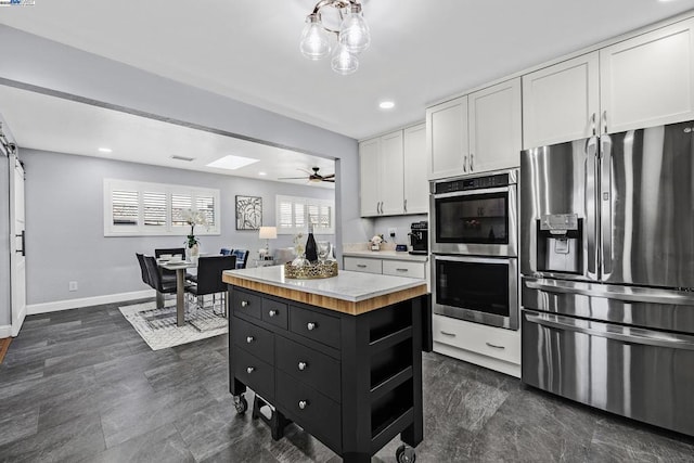 kitchen featuring white cabinetry, ceiling fan, stainless steel appliances, and a kitchen island